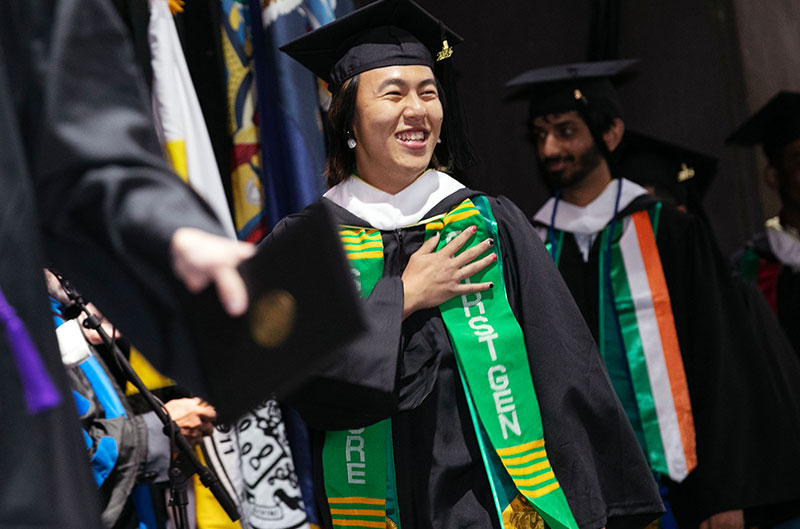 A student wearing a "first gen" stole graduates from college